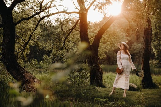 Portrait of a beautiful woman in a white dress and a hat with lilies of the valley at sunset. A girl in nature. Spring flowers.