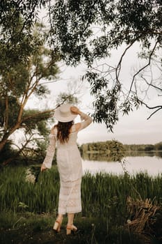 Portrait of a beautiful woman in a white dress and a hat with lilies of the valley. A girl in nature. Spring flowers.