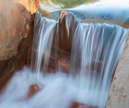 Closeup detail of blurred water in hot spring pool trough at african egyptian oasis spring well