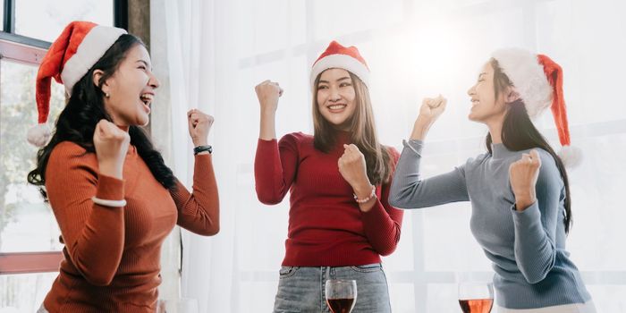 Group of Asian friends gather to celebrate Christmas with champagne and eating pizza at home. Joy of holiday party with friends or colleague concept.