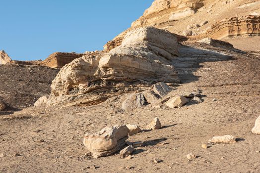 Rocky slope landscape in an arid desert environment with large pyramid mountain at top