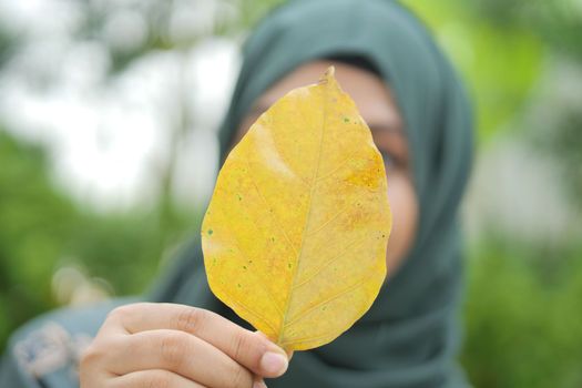 women cover her face with Dry brown leaf .
