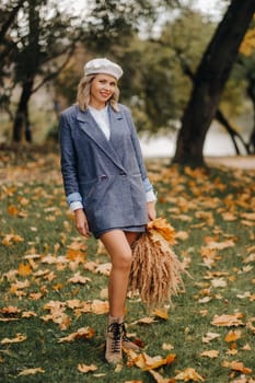 Portrait of a Girl in a jacket and birette with an autumn bouquet in an autumn park.