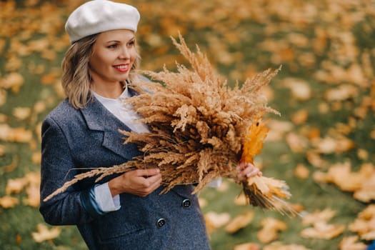 Portrait of a Girl in a jacket and birette with an autumn bouquet in an autumn park.