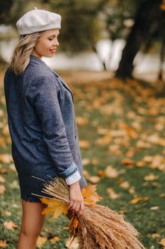 Portrait of a Girl in a jacket and birette with an autumn bouquet in an autumn park.