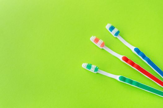 Multicolored toothbrushes on a green background, the concept of dental care and oral hygiene. Place for an inscription