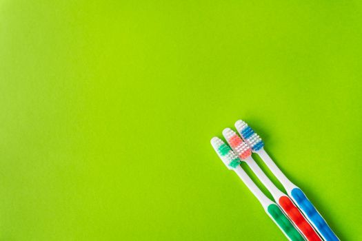 Multi-colored toothbrushes on a green background, the concept of dental care and hygiene. Place for an inscription