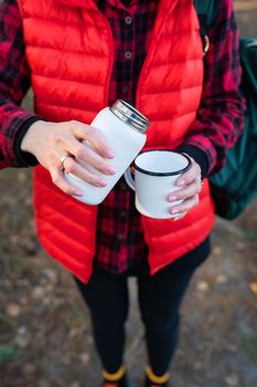 A girl pours hot tea from a thermos, a snack in the open air.Travel, trekking and hiking