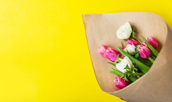 Red and white bouquet of tulips and anemones flowers on a yellow background. With copy space