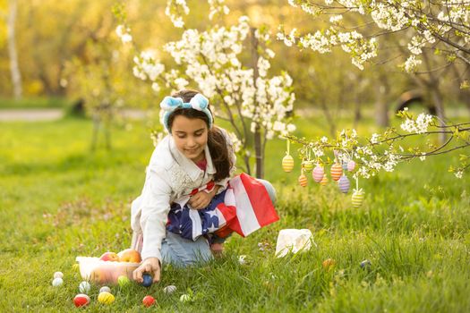 A teenage girl in a blooming garden at Easter with a US flag.