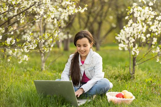 Smart little girl using her laptop in the garden