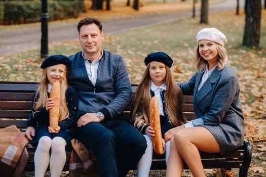 A large family is sitting on a bench in an autumn park. Happy people in the autumn park.