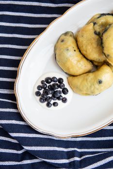 Sweet fruit dumplings with fresh forest blueberries. Homemade fresh dumplings on a plate along with sour cream