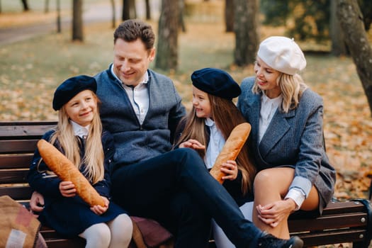 A large family is sitting on a bench in an autumn park. Happy people in the autumn park.