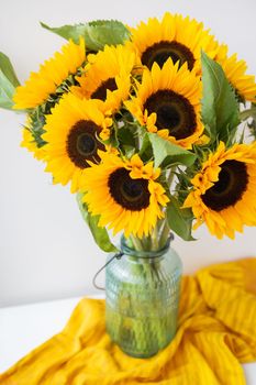 A beautiful bouquet of sunflowers stands in a vase on the table. Floral work. Bouquet for birthday or wedding in rustic style