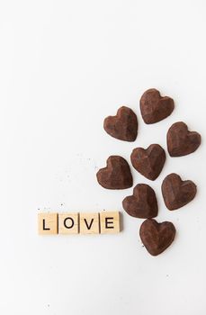 The inscription in wooden letters love, small truffle candies in the form of a heart