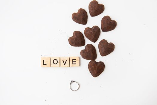 The inscription in wooden letters love, small truffle candies in the form of a heart. Ring with a diamond - a proposal of a hand and a heart