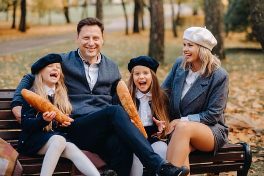 A large family is sitting on a bench in an autumn park. Happy people in the autumn park.