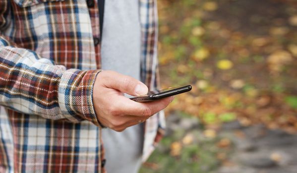 A man on a city street looks into his smartphone. The world of mobile communications and the Internet