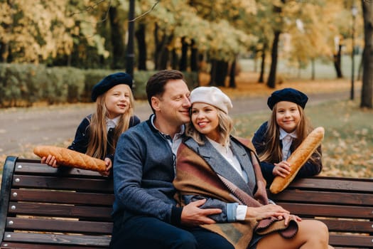 A large family is sitting on a bench in an autumn park. Happy people in the autumn park.