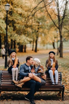 A large family is sitting on a bench in an autumn park. Happy people in the autumn park.