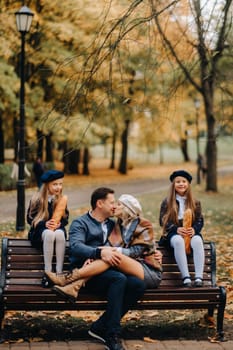 A large family is sitting on a bench in an autumn park. Happy people in the autumn park.