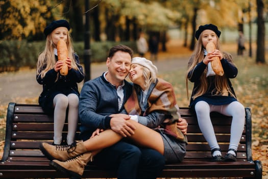 A large family is sitting on a bench in an autumn park. Happy people in the autumn park.