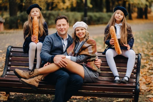 A large family is sitting on a bench in an autumn park. Happy people in the autumn park.