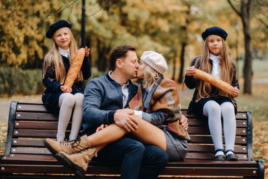 A large family is sitting on a bench in an autumn park. Happy people in the autumn park.