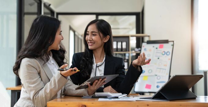 Two young Asian businesswoman discuss investment project working and planning strategy. Business people talking together with laptop computer at office..