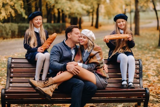 A large family is sitting on a bench in an autumn park. Happy people in the autumn park.