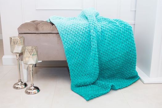Background texture of plush fabric in aquamarine green color, background pattern of soft woolen material that lies on a small sofa along with candlesticks, cozy concept