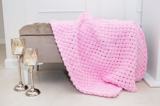 Background texture of plush fabric in pink color, background pattern of soft woolen material that lies on a small sofa along with candlesticks, cozy concept