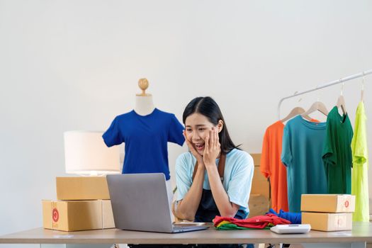Happy exciting successful asian woman doing clothing business selling online. she using laptop computer. online sell marketing delivery, SME e-commerce telemarketing concept.