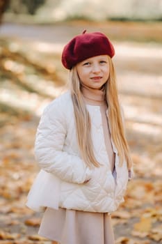 A happy girl in a cap walking in the autumn park.