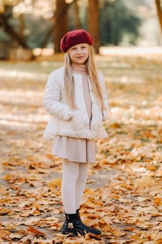A happy girl in a cap walking in the autumn park.