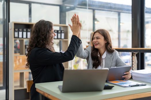 Two happy friendly diverse professionals, cheerful successful business partners colleagues giving high five celebrating business triumph in office.