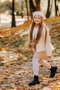 A happy girl in a cap walking in the autumn park.