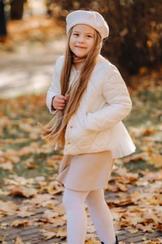 A happy girl in a cap walking in the autumn park.