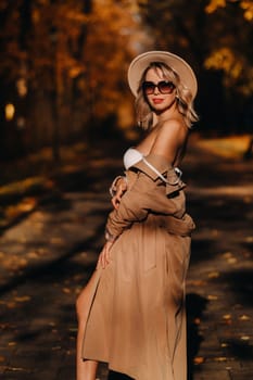 Sexy girl in a coat and hat in an autumn sunny park.