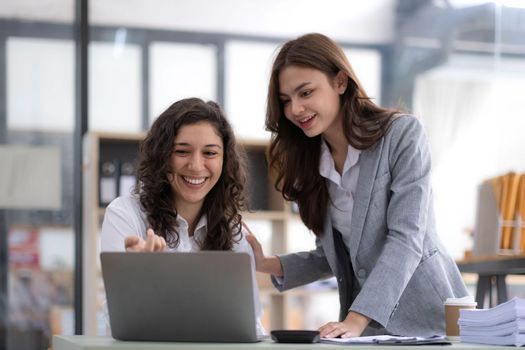 Two young Asian business woman talk, consult, discuss working with new startup project idea presentation analyze plan marketing and investment in the office..