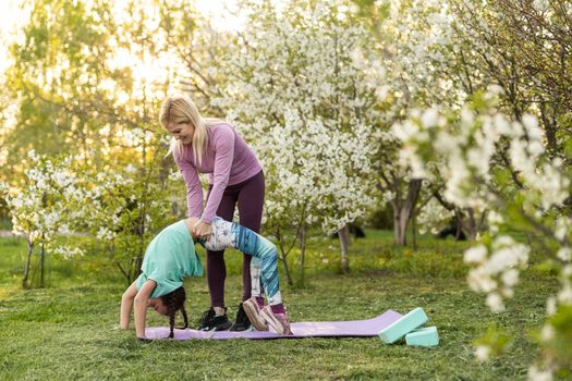 two young women and a little girl in their garden doing yoga.
