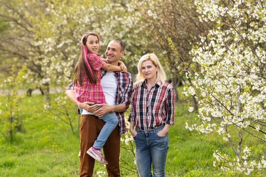 Happy family spending good time together in spring in a flowering garden.