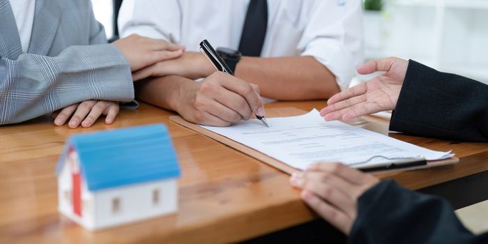 Young couple signing contract agreement with real estate agent