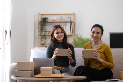Portrait of Starting small businesses SME owners, two Asian woman check online orders Selling products working with boxs freelance work at home office, sme business online small medium enterprise.
