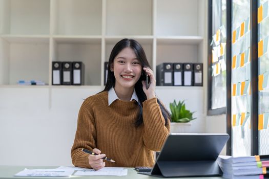 Portrait young asian businesswoman beautiful charming smiling and talking on the mobile phone in the office