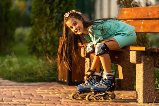 little girl wears roller skates on beautiful summer day in a park.