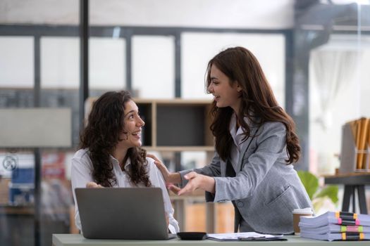 Two young Asian business woman talk, consult, discuss working with new startup project idea presentation analyze plan marketing and investment in the office..