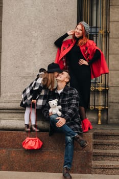 A stylish family of three strolls through the autumn city posing for a photographer . Dad, mom and daughter in the autumn city.