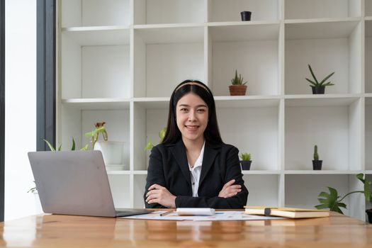 Portrait confidence asian business woman looking on camera sitting at work desk in office